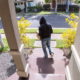 Person stealing delivery package from porch steps, surveillance camera view